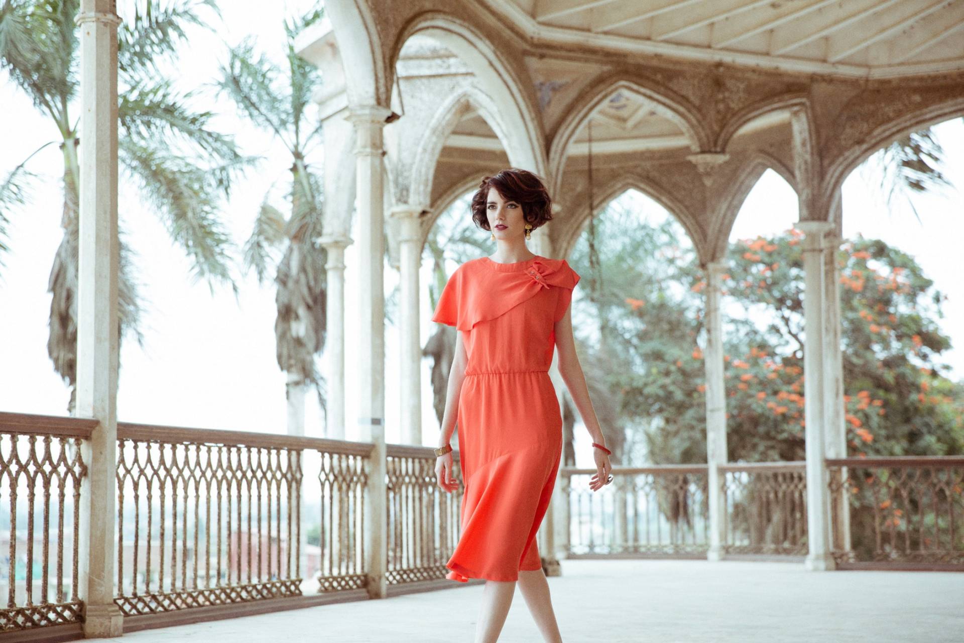 Foto moda, muestra una modelo con un vestido naranja en exterior.